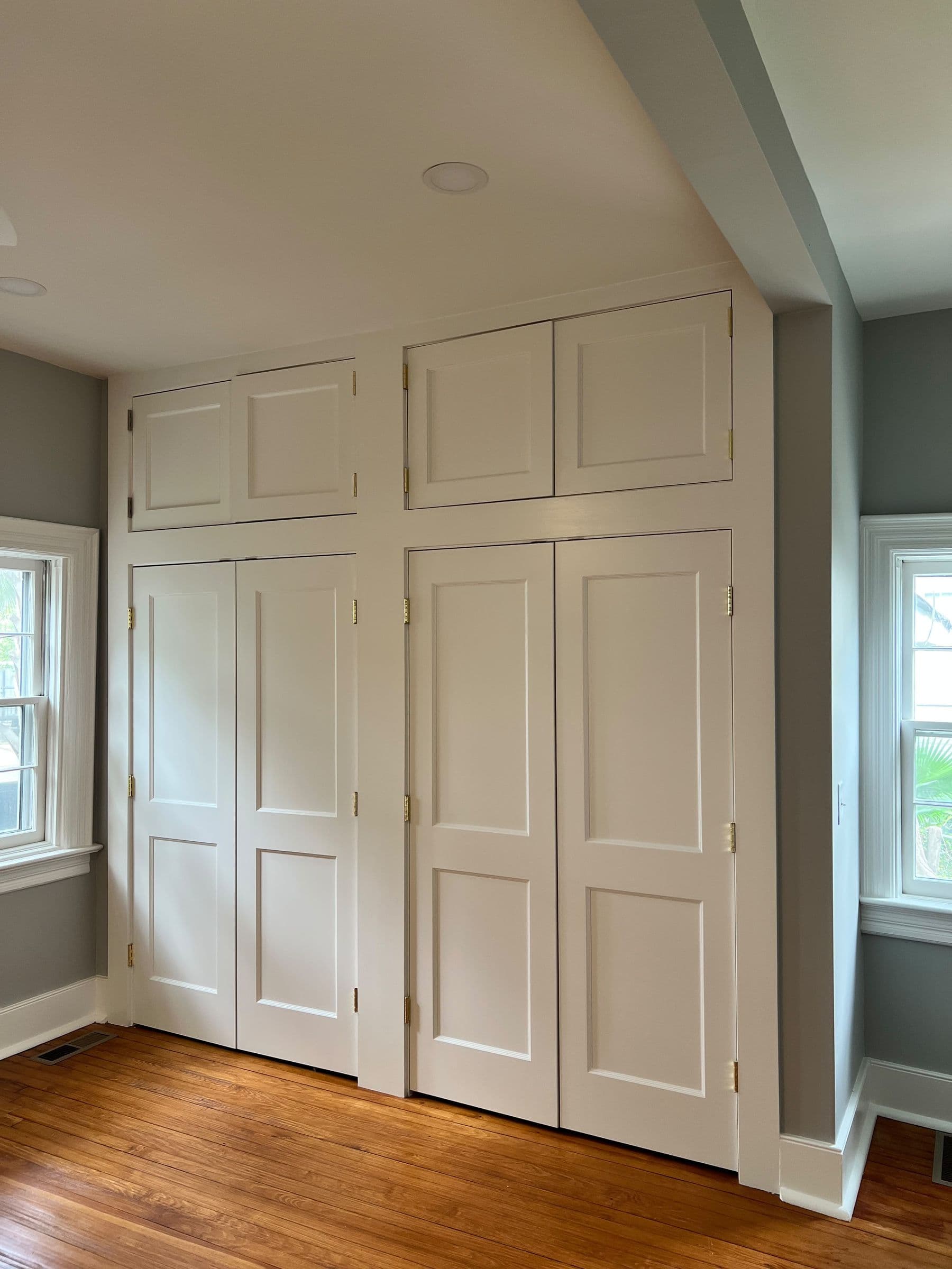 Built-in paneled closet doors between two windows
