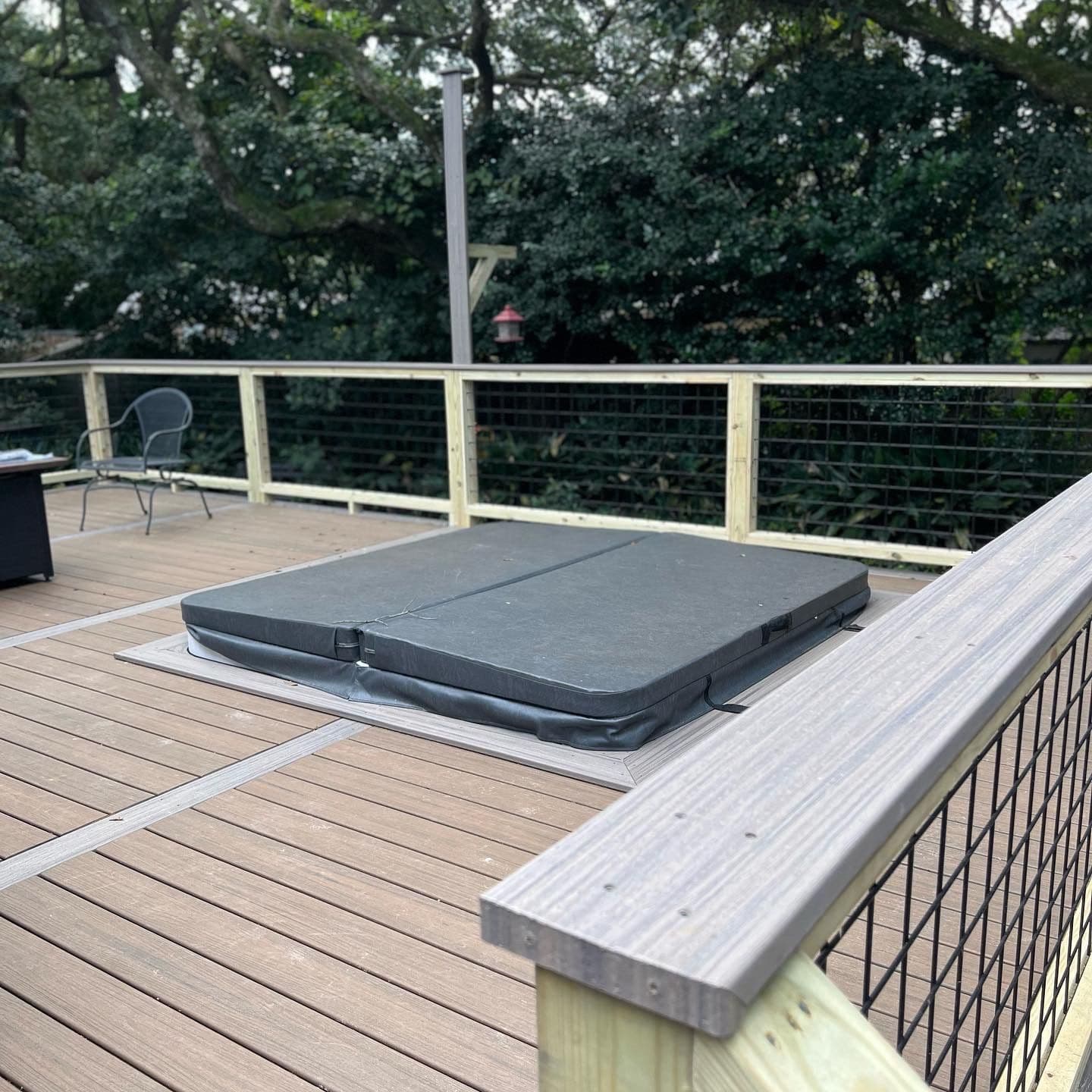 Composite deck built around a flush-set hot tub with cable railing