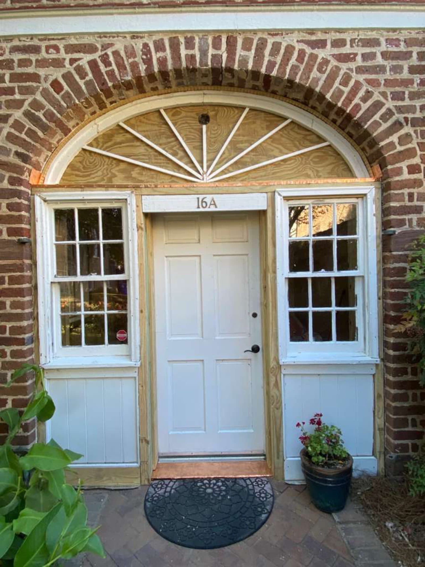 Entry door set under a brick arch with a fanlight and sidelights