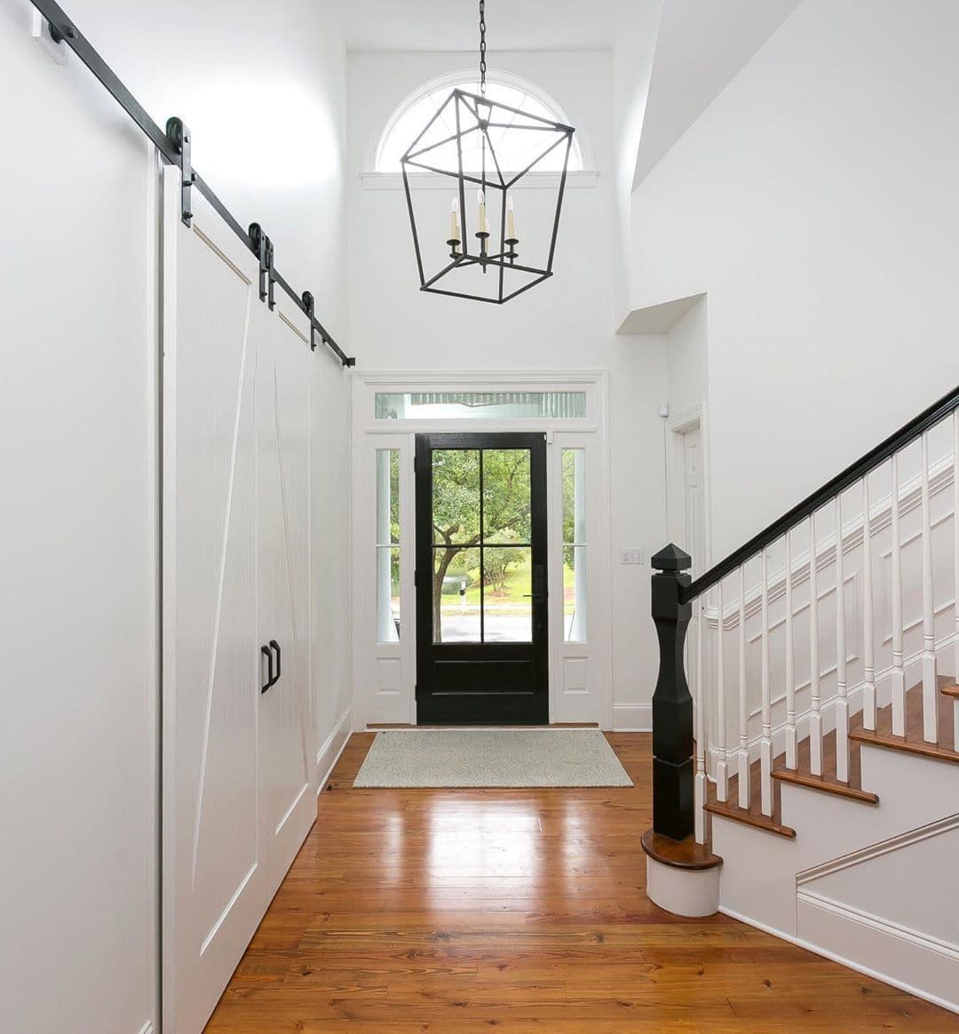Foyer with barn doors, stair newel and heart pine floor