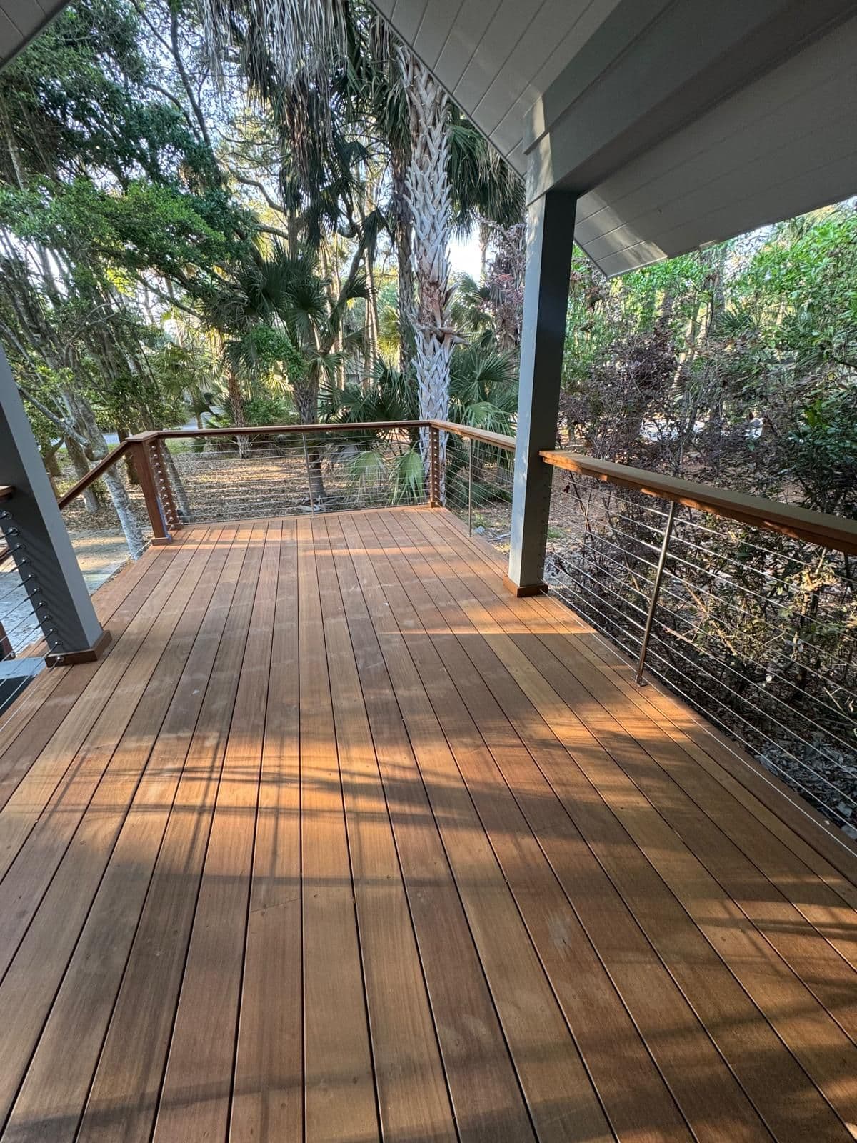 Hardwood deck with cable railing under a covered porch