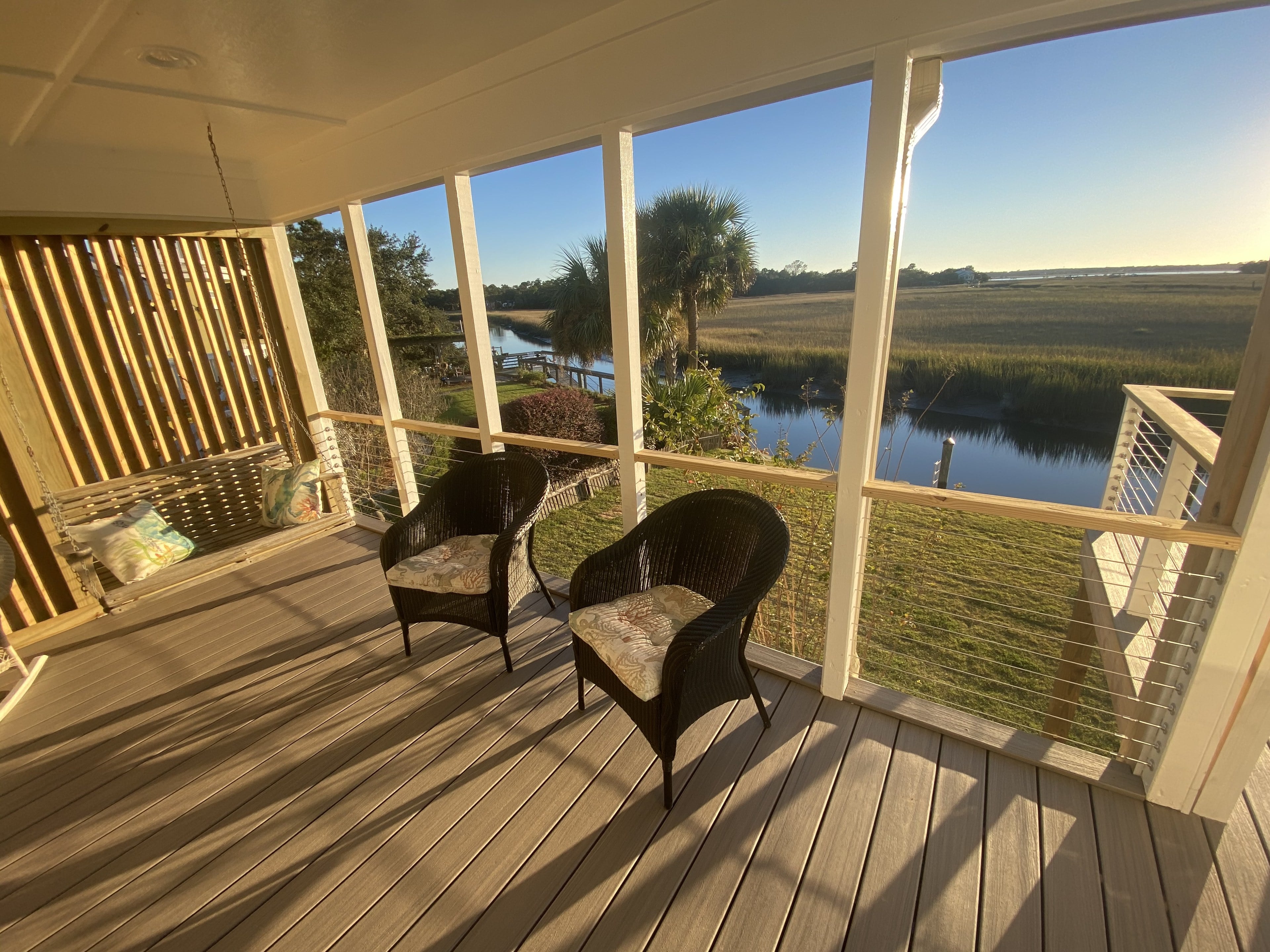 Screened porch with composite floor and cable rail looking out over the marsh at sunset