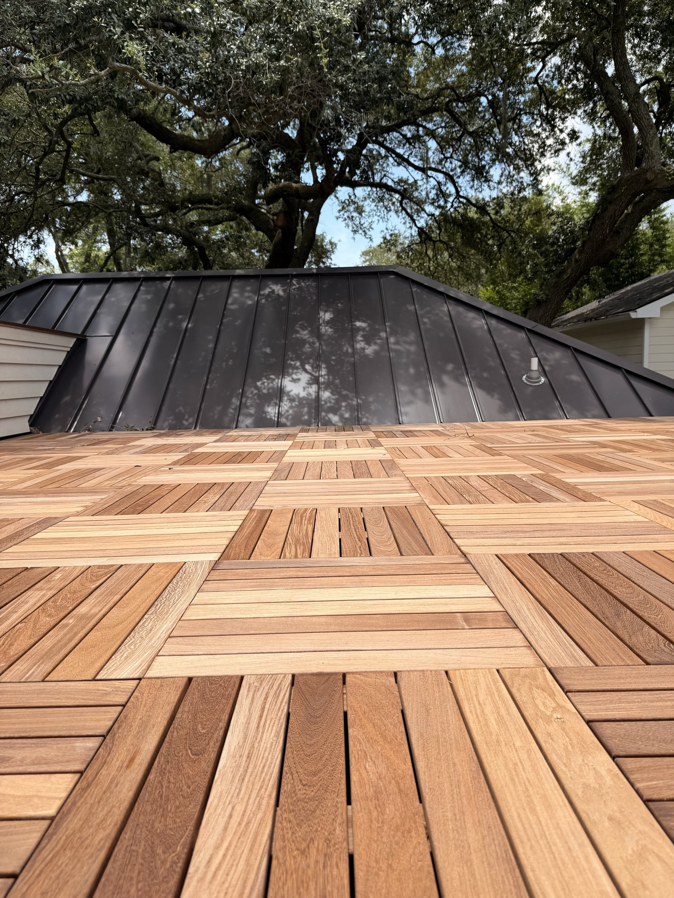 Ipe deck tiles laid in a basket-weave pattern on a rooftop deck under live oaks