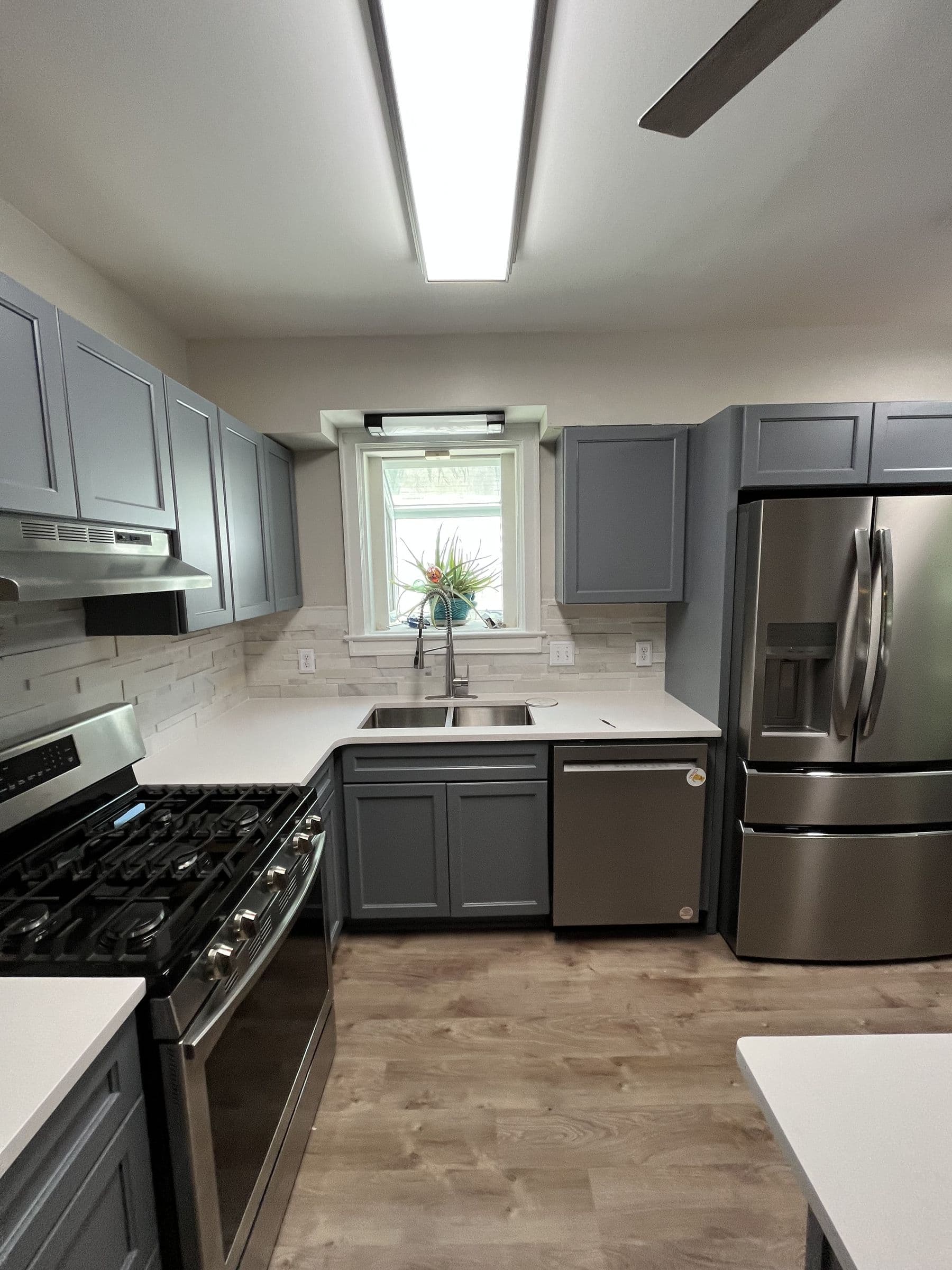 Renovated kitchen with gray shaker cabinets, quartz counters and new flooring