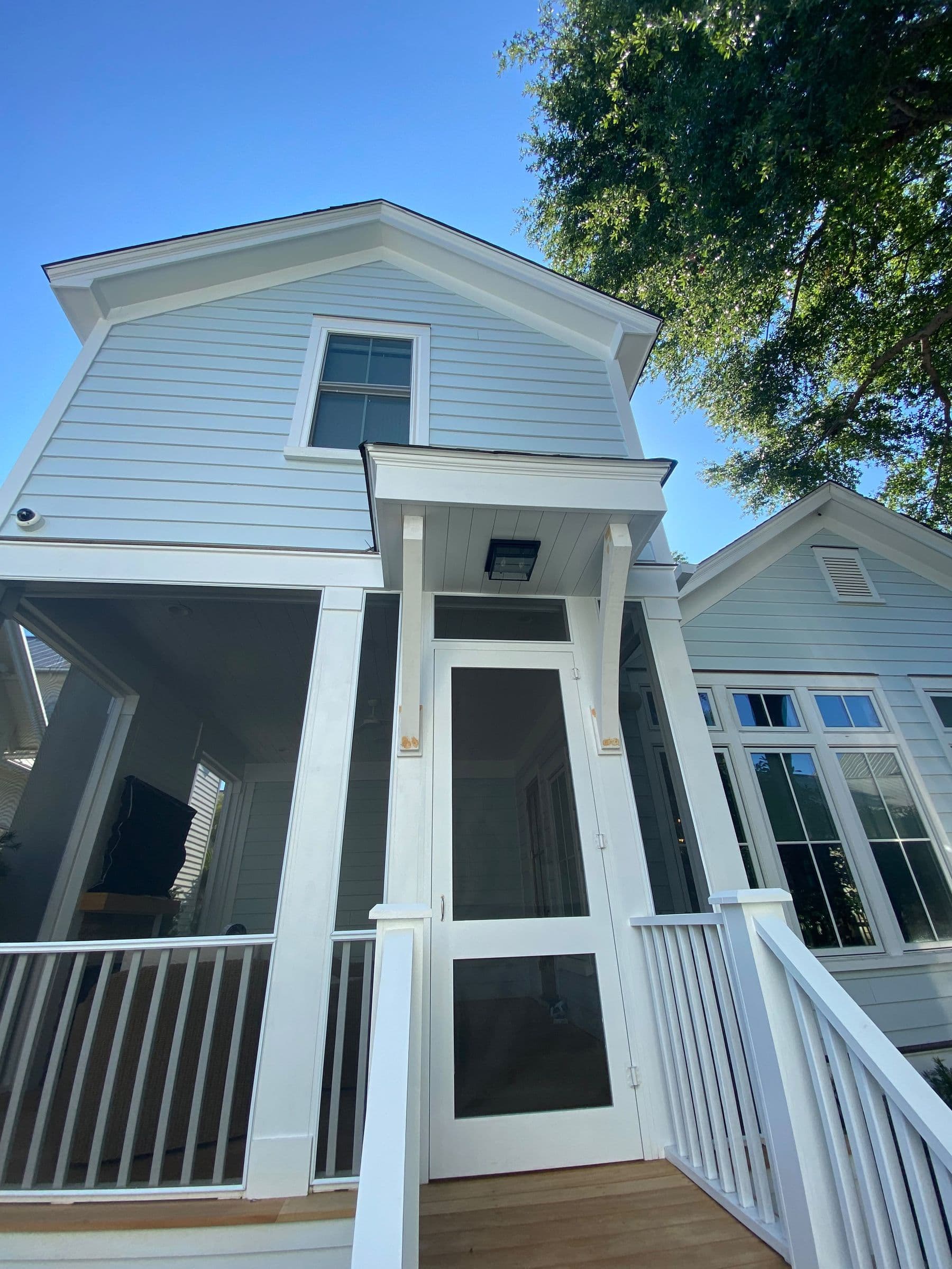 Two-story house with a raised screened porch and white stair
