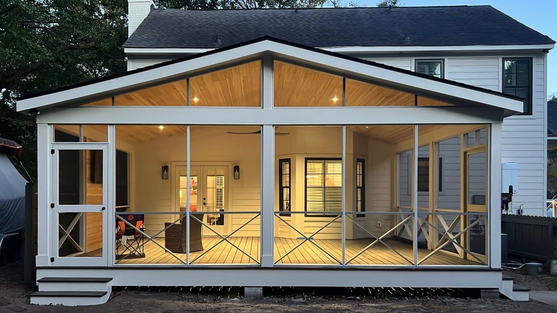 Gabled screened porch addition lit at dusk with a tongue-and-groove ceiling