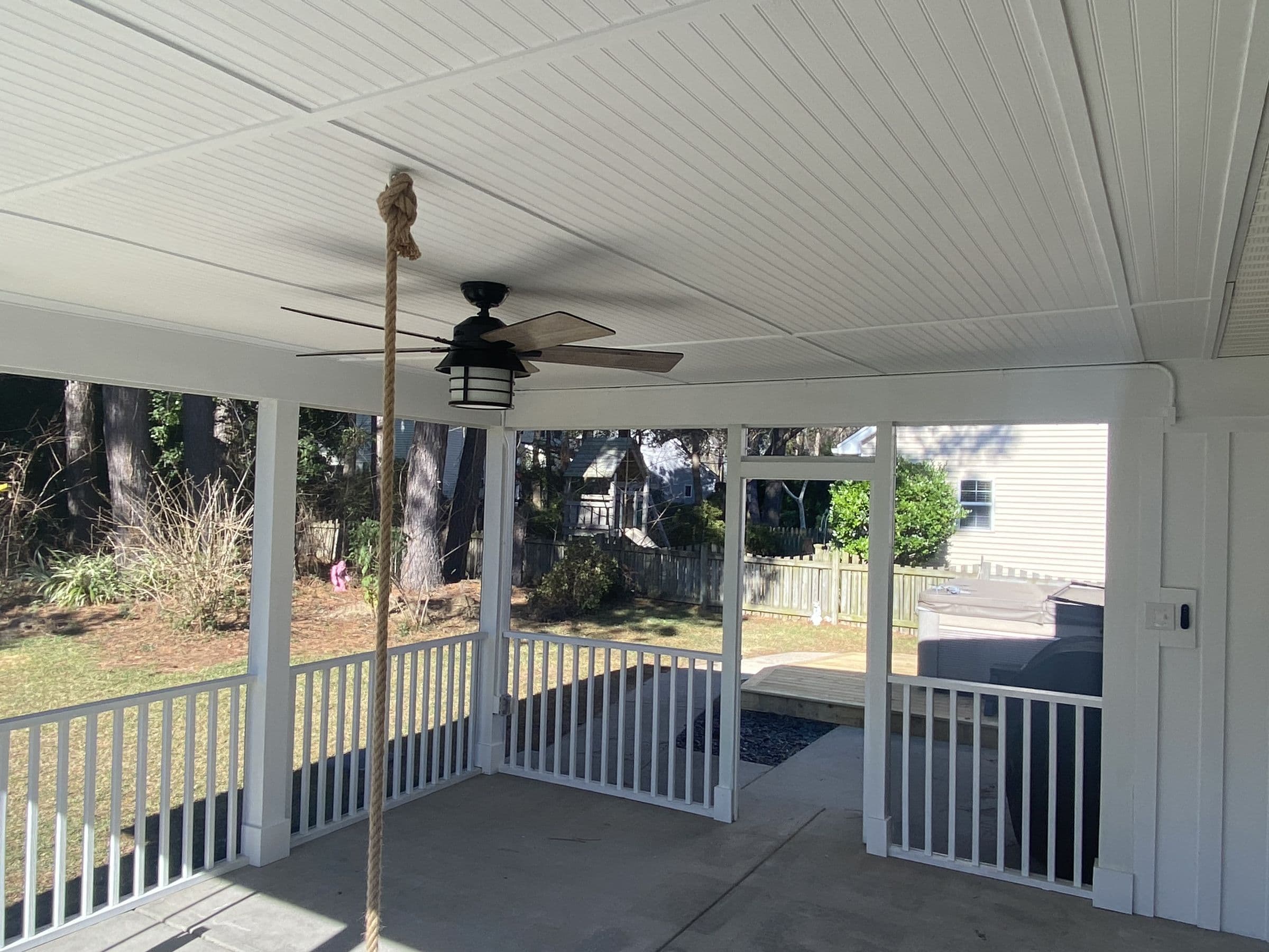 Inside a finished screened porch with a beadboard ceiling and ceiling fan